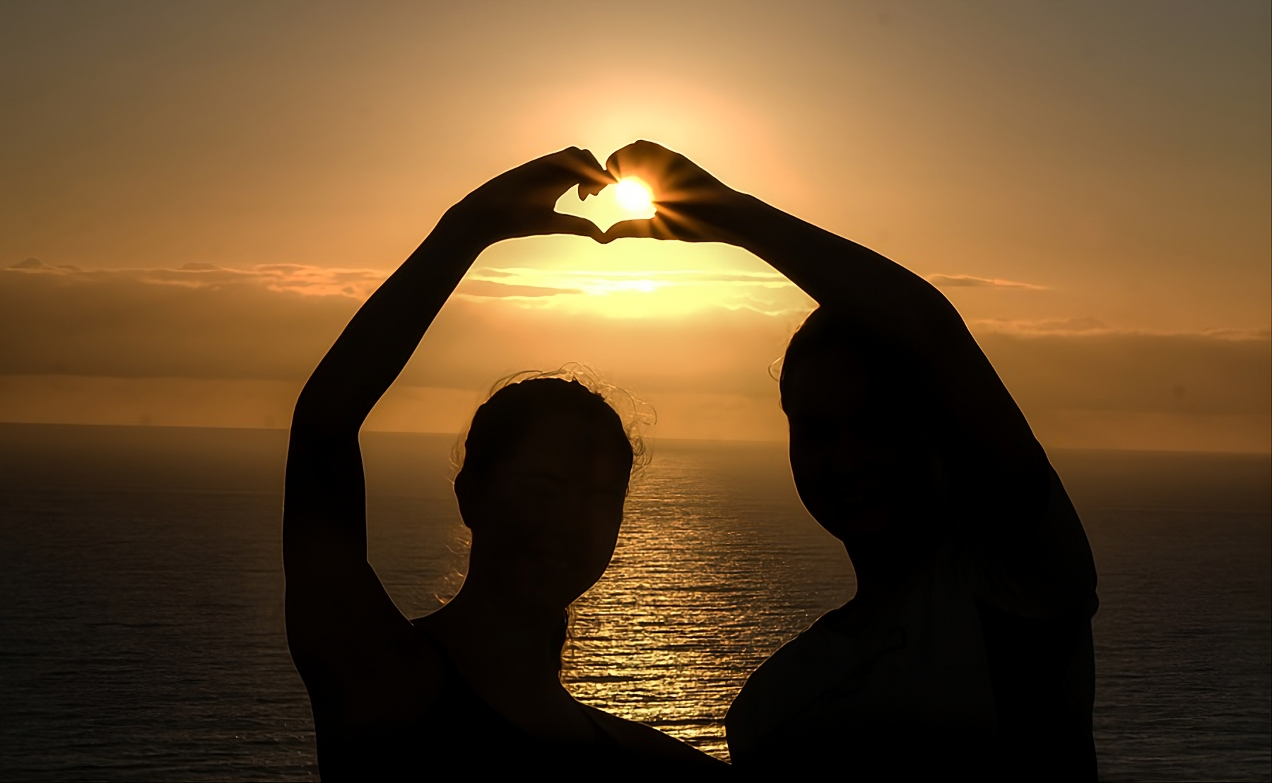 elever former et hjerte med hendene ved solnedgang