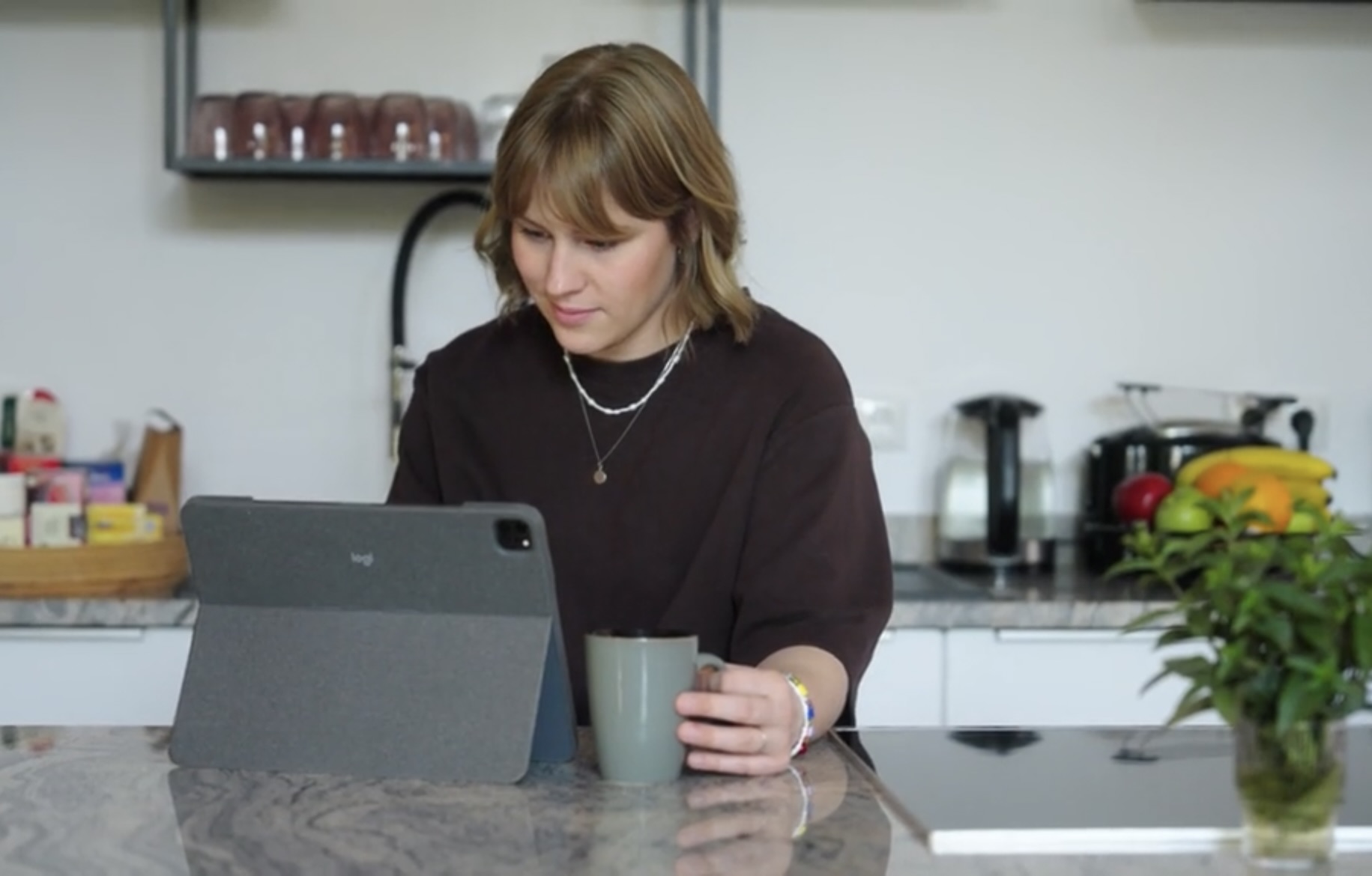 Frau trainiert zu Hause am Küchentisch mit RehaCom auf dem Tablet