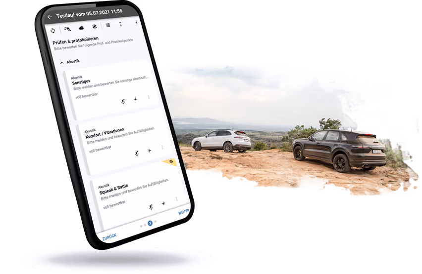 Smartphone screen displaying an app interface in German about acoustics testing, next to two SUVs parked on rocky terrain with a distant landscape view.