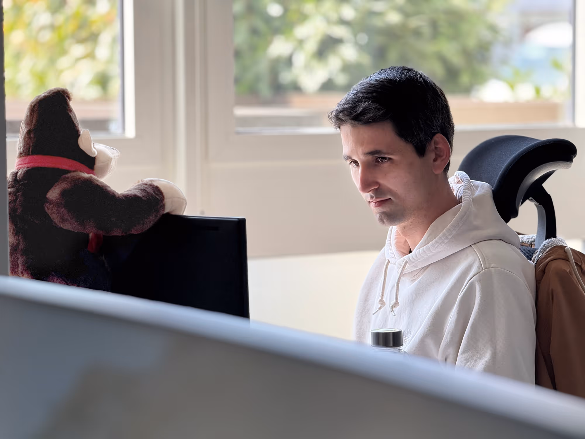 King Kong pet is sitting behind an employees Screen watching him work.
