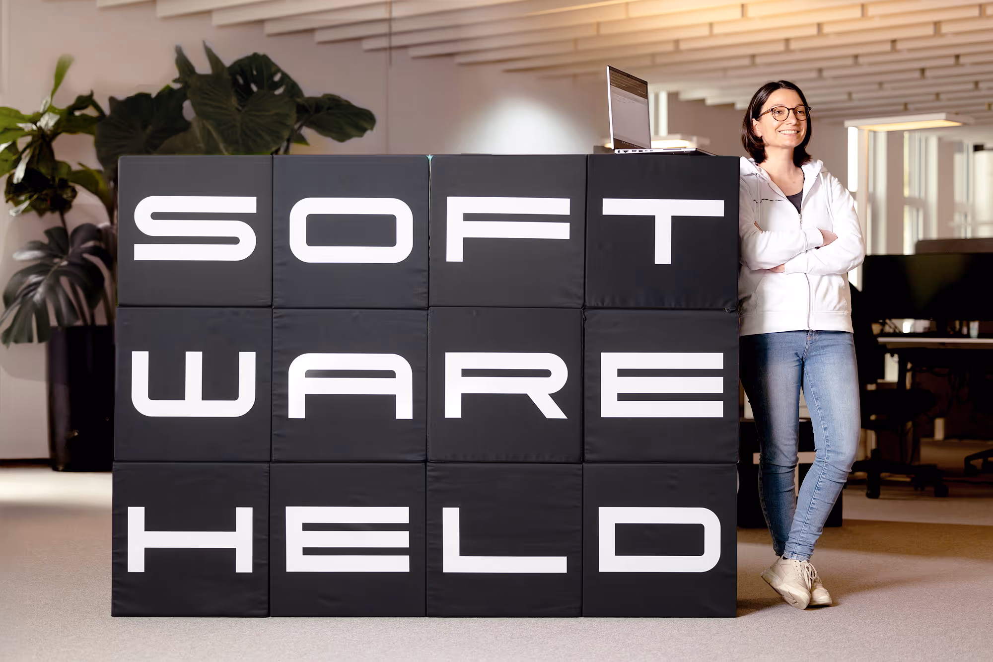 Woman leaning relaxed on a wall showing a softwarehelden logo