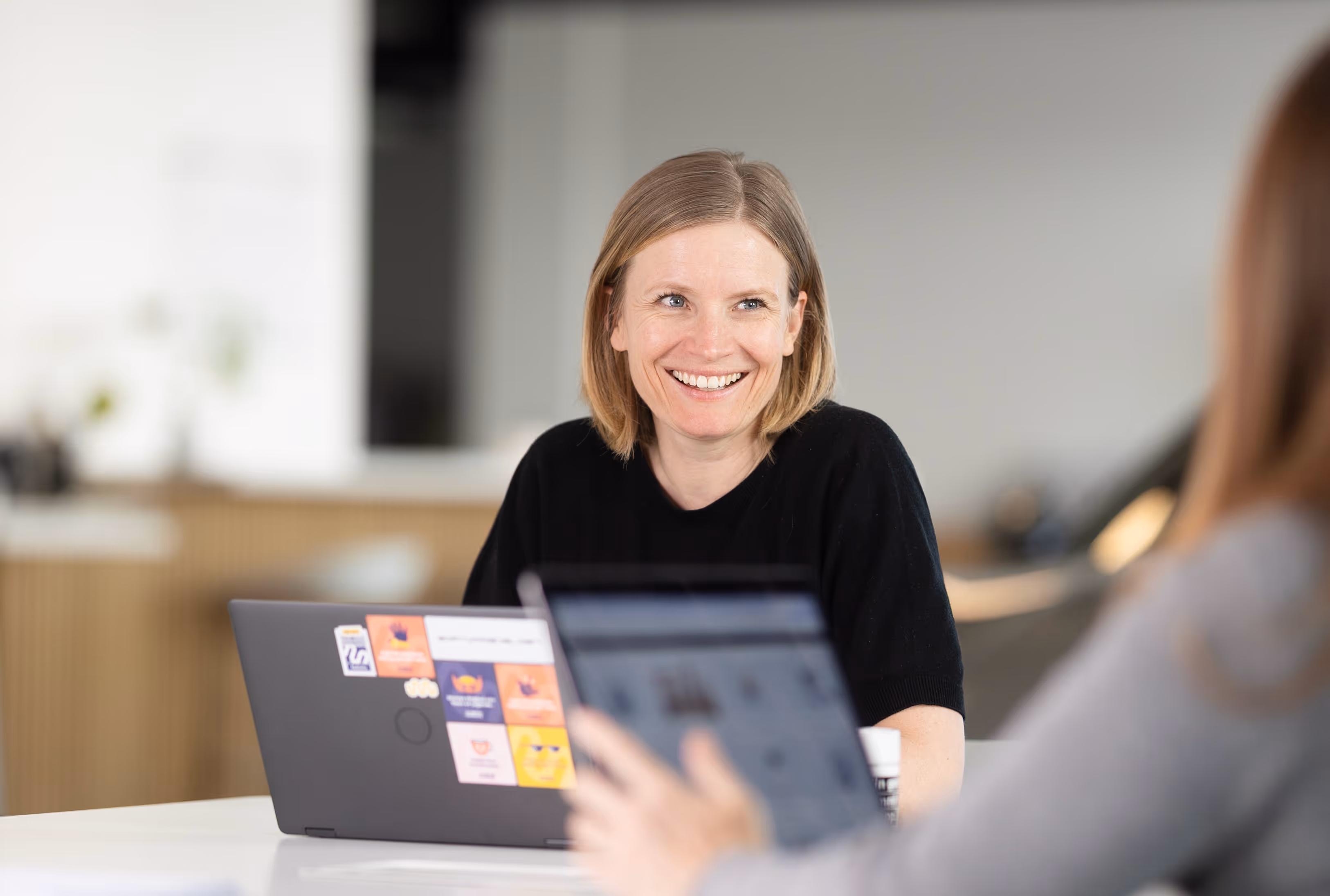 Conversation between two women in the softwarehelden office. They are smiling.