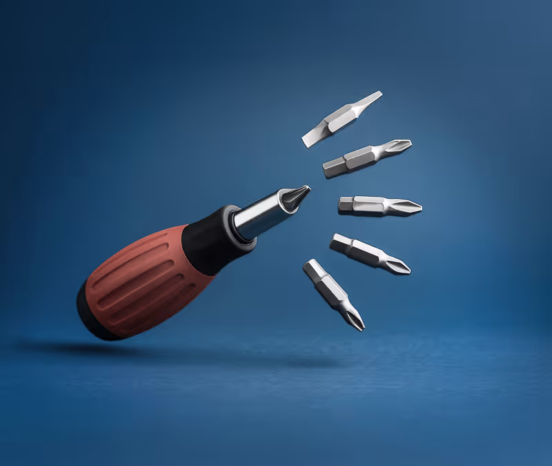 Red and black screwdriver handle with five interchangeable metal bits floating nearby on a blue background.