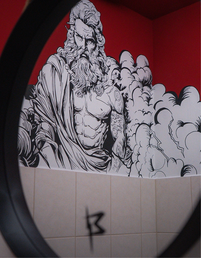 Black and white tattoo-style mural of a muscular bearded man on a red wall seen through a round mirror.