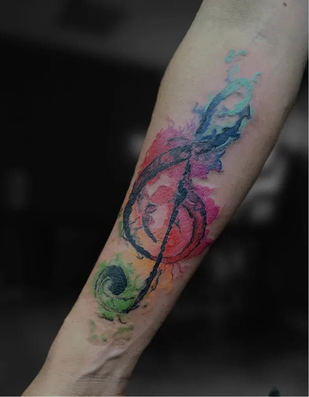 Black and grey tattoo of a realistic eye above a skull with a tree and hanging figures on the arm.