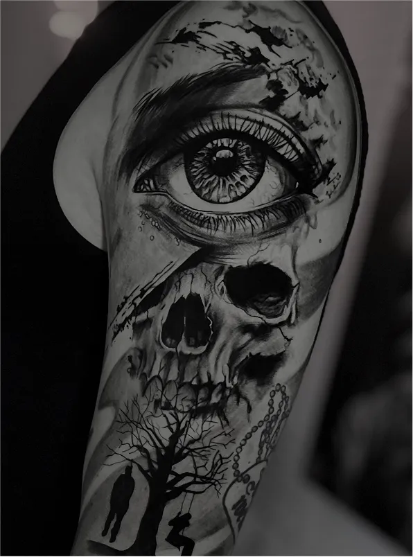 Black and grey tattoo of a realistic eye above a skull with a tree and hanging figures on the arm.