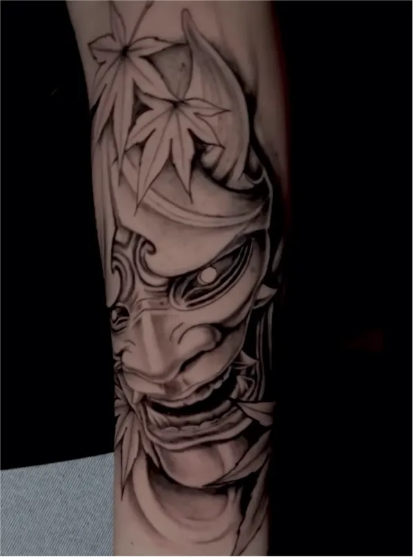 Black and grey tattoo of a realistic eye above a skull with a tree and hanging figures on the arm.