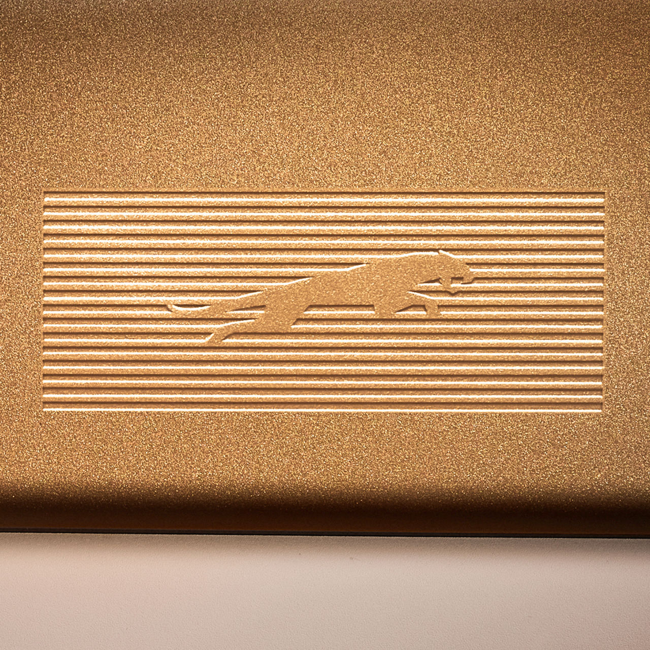 Détail de l’emblème Jaguar (leaper) dans une finition inspirée du laiton
