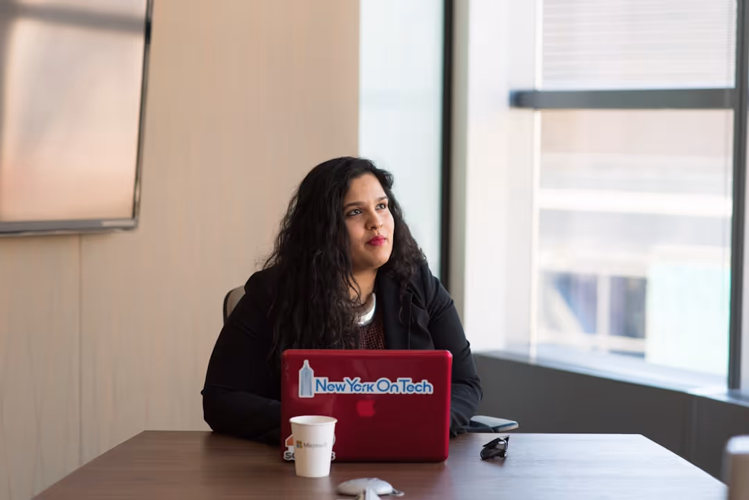A woman sitting at a desk with a laptop and a cup of coffee.