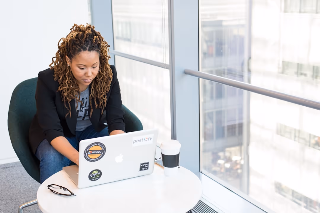 A woman sitting at a table with a laptop and a cup of coffee.