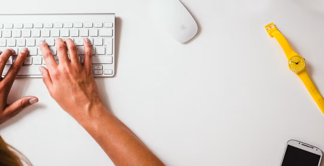 A person's arm with a keyboard and mouse on a white table.