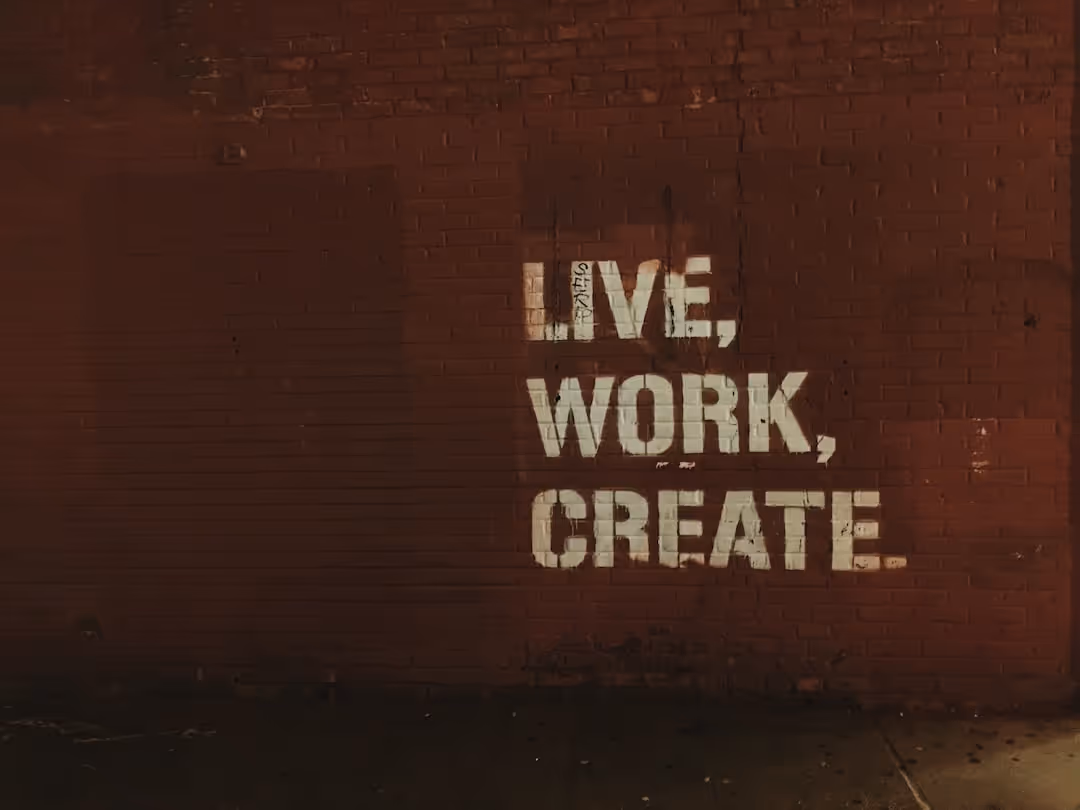 A red brick wall with a white sign that says Live, Work, Create.