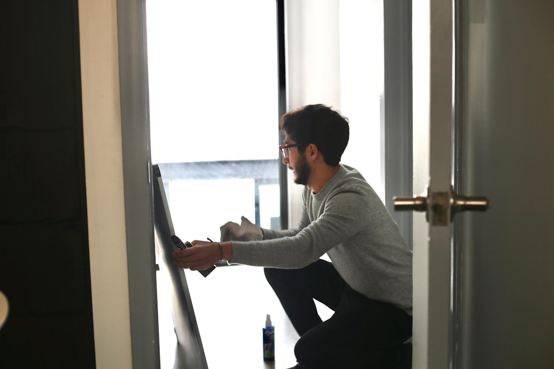 man in gray long sleeve shirt and black pants sitting on window during daytime