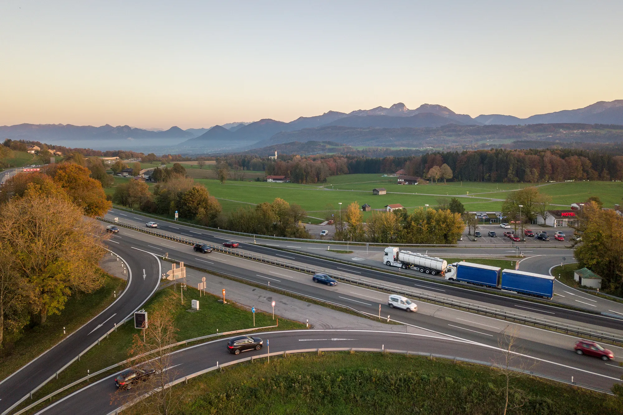 A view of a highway with a blue car and a white truck driving on it.