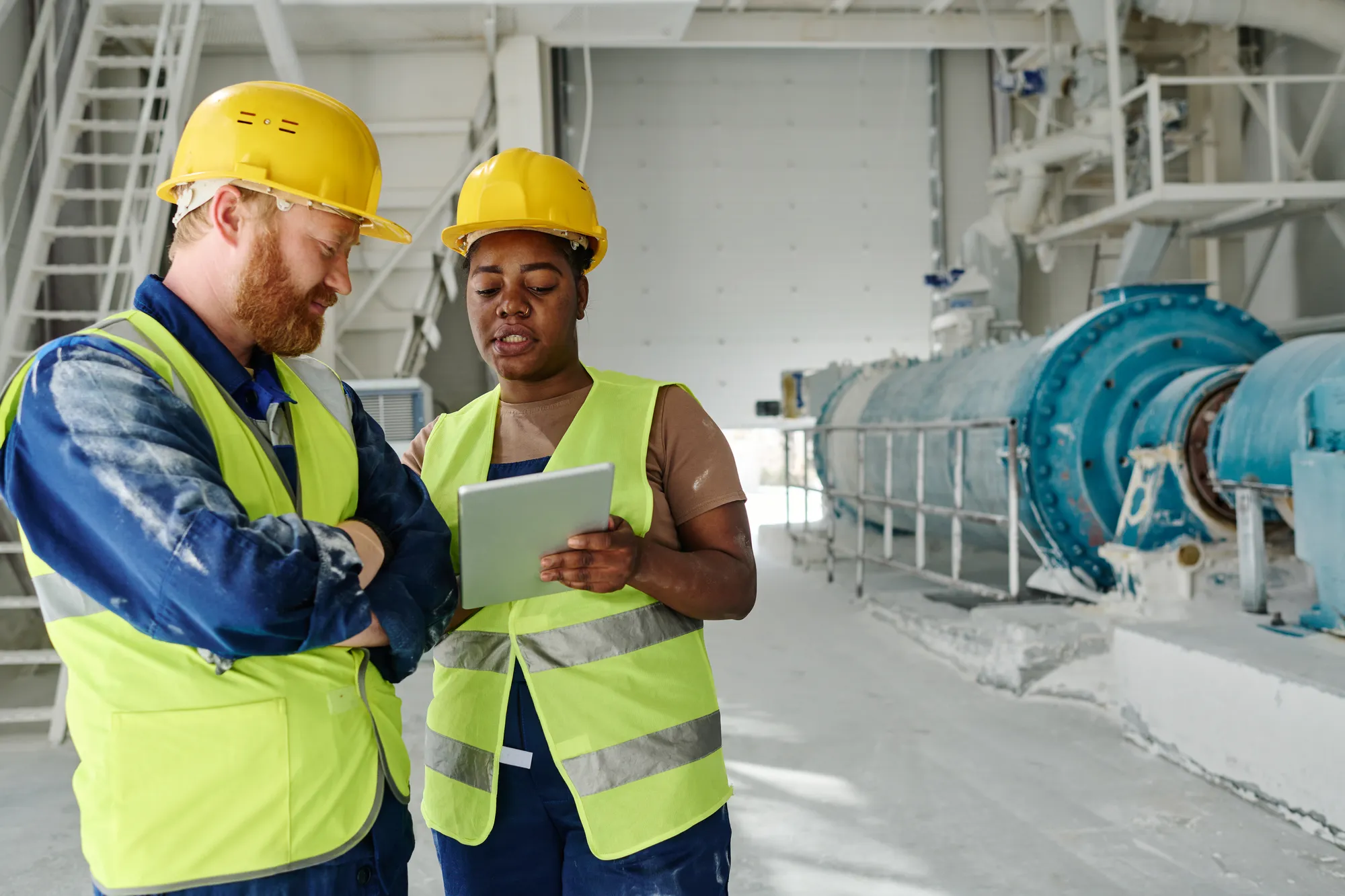 Two construction workers looking at a tablet.