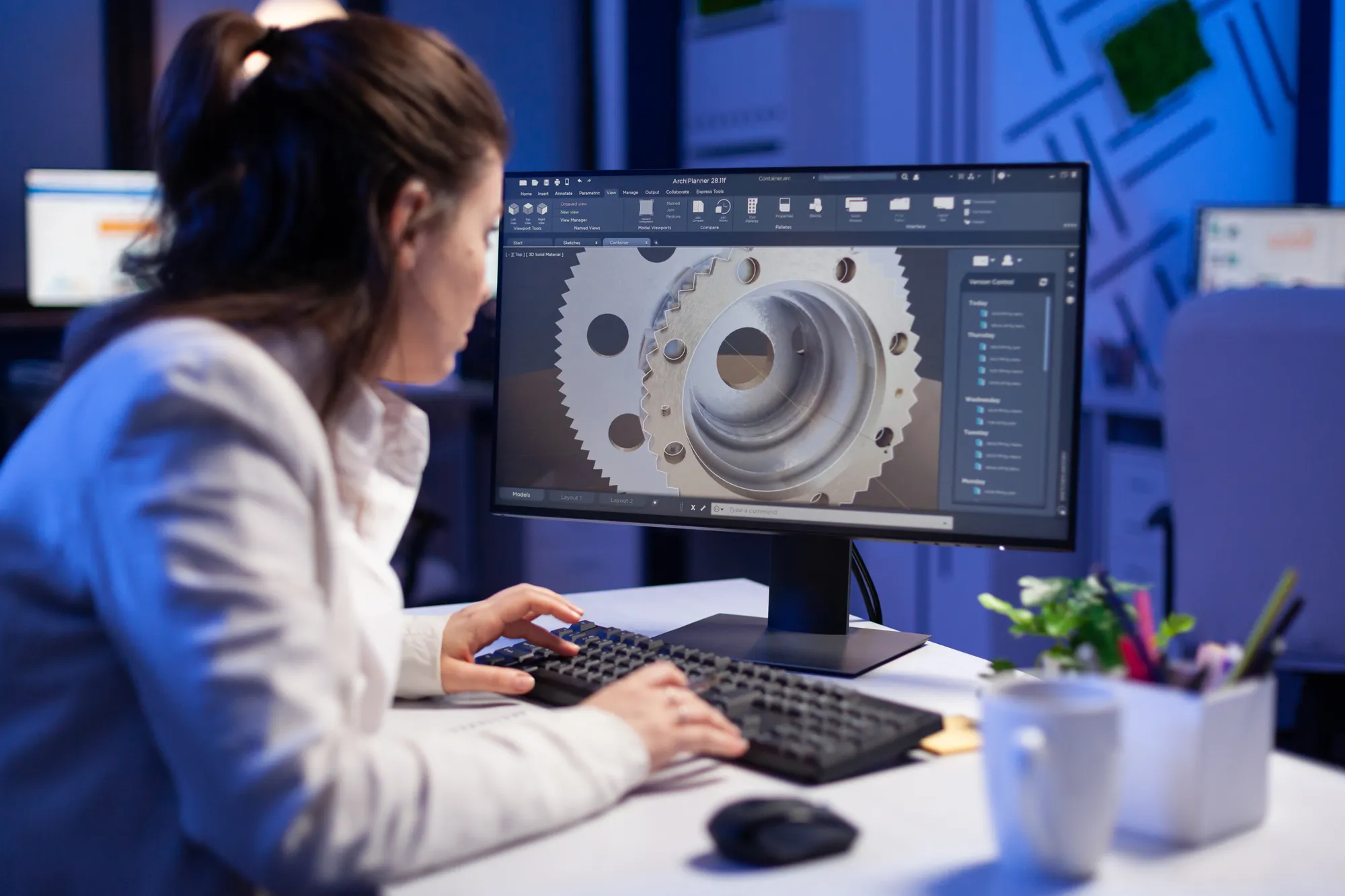 A woman is working on a computer with a large monitor.