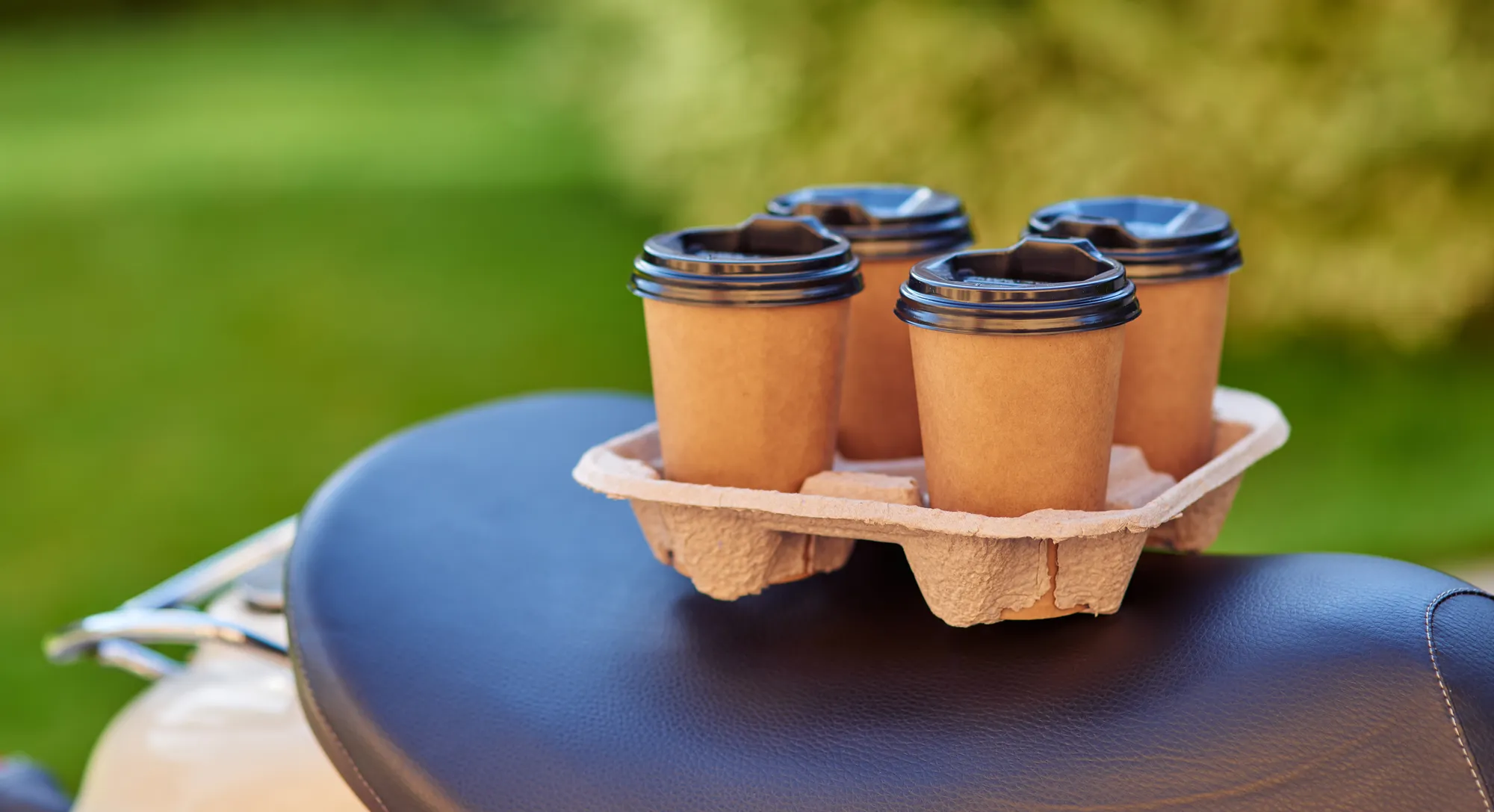 A brown cup with a black lid on a tray.