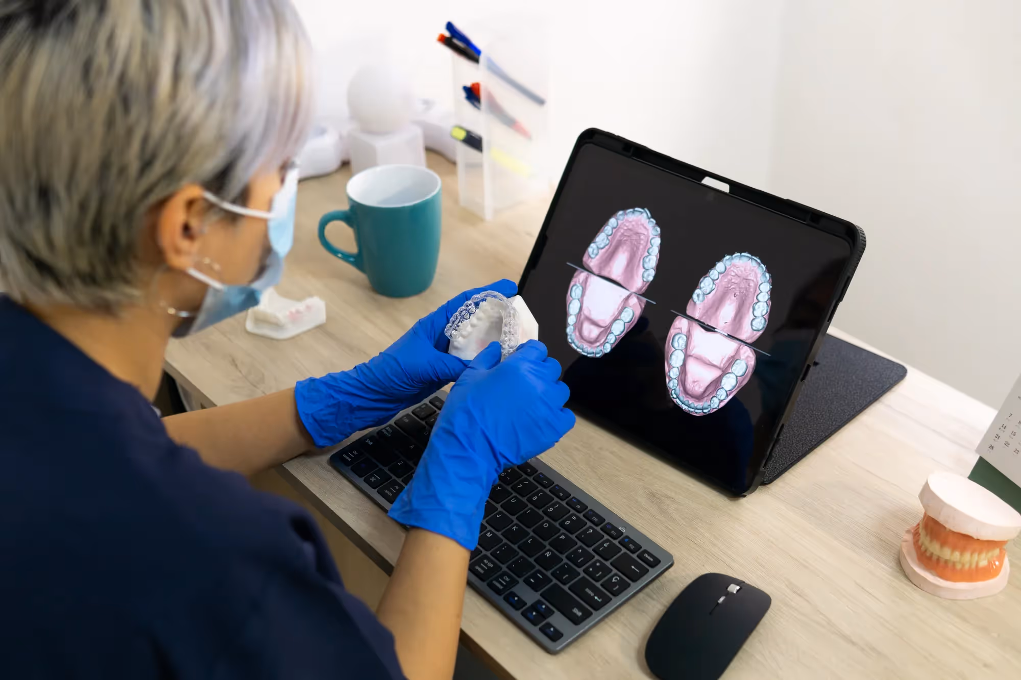 A woman wearing a face mask is using a laptop.
