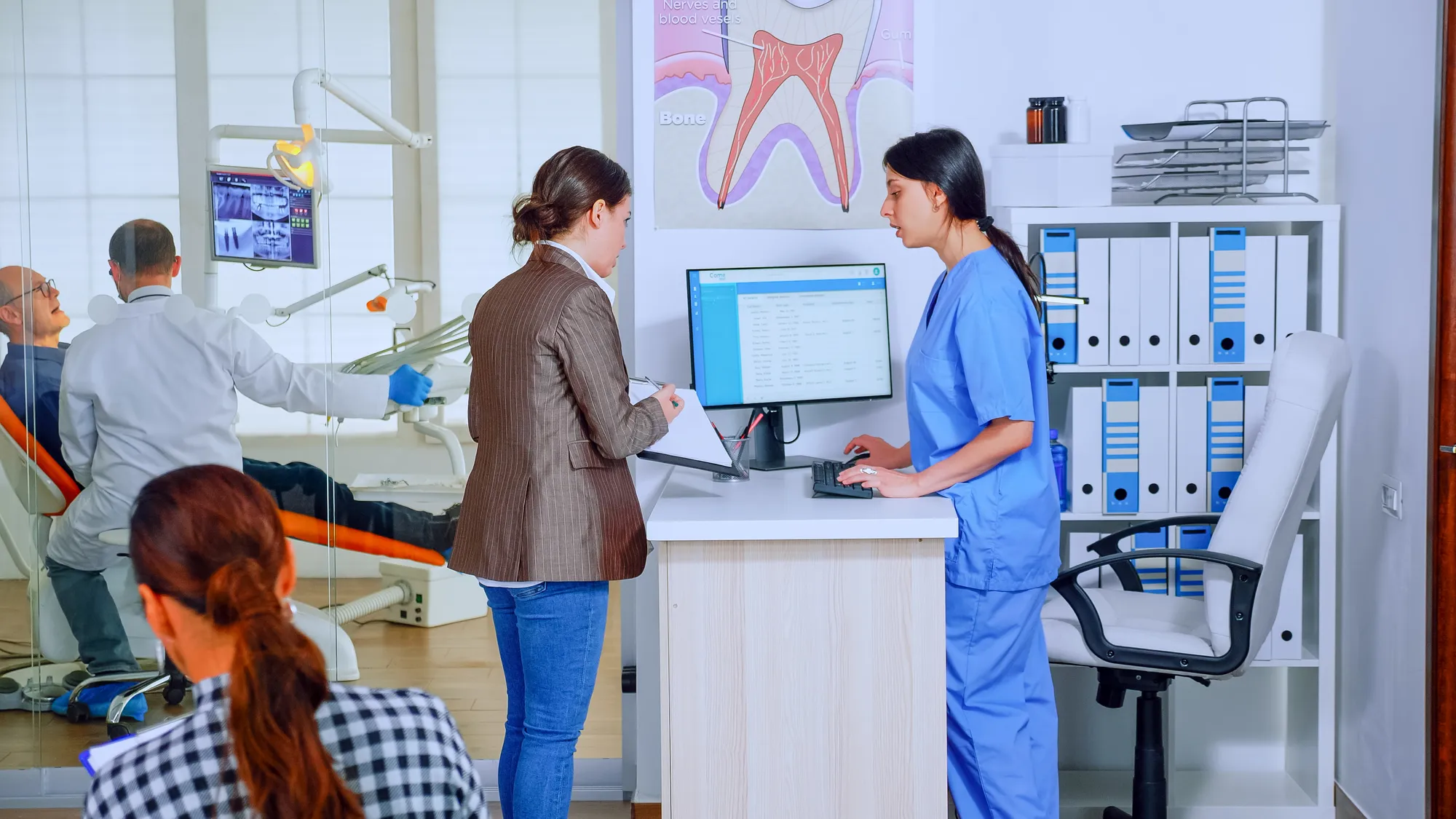 A woman in a blue shirt is working on a laptop.