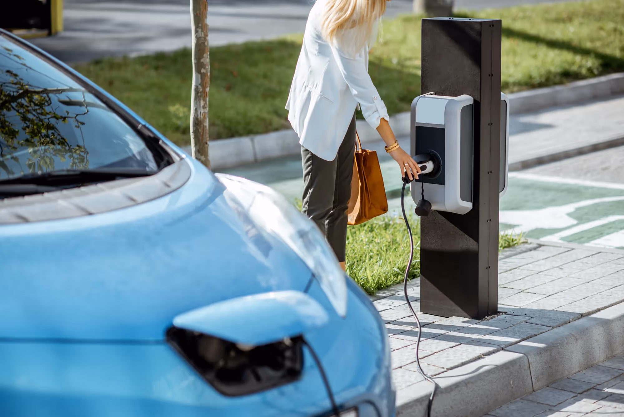 A woman is plugging her car into a charging station.