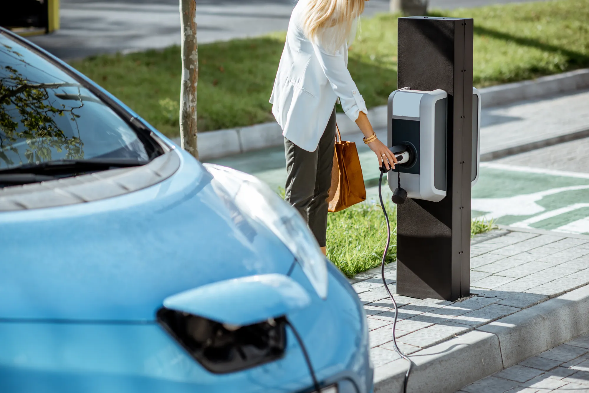 A woman is plugging her car into a charging station.