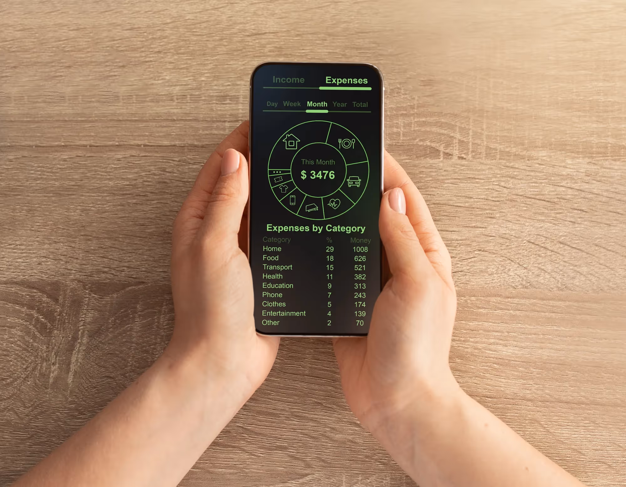 A person holding a cell phone with a green screen displaying expenses.