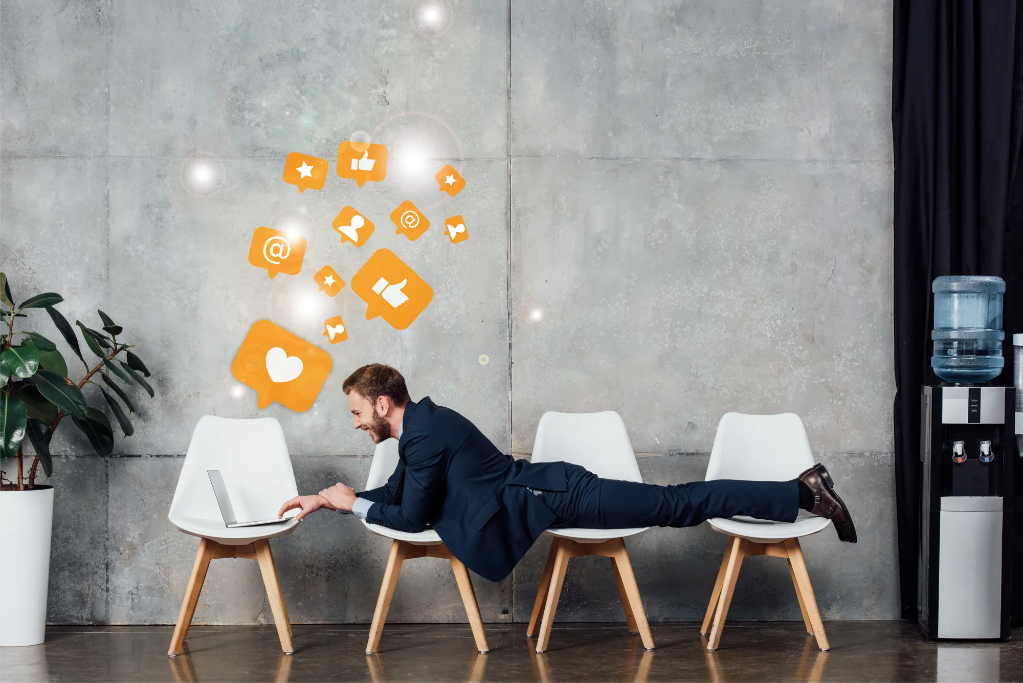 A man is laying on a chair with a laptop in front of him.