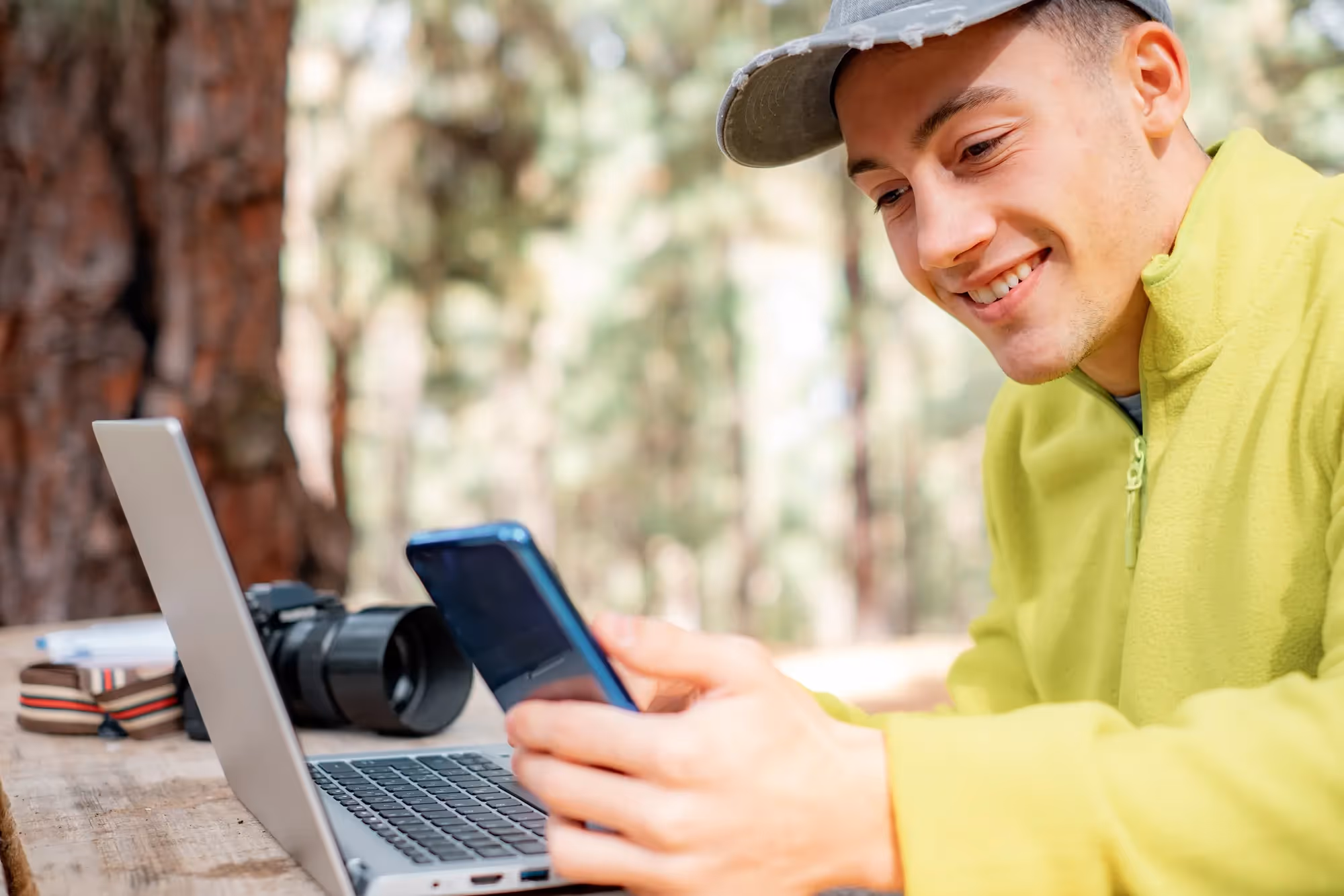 A man wearing a yellow shirt is holding a cell phone.