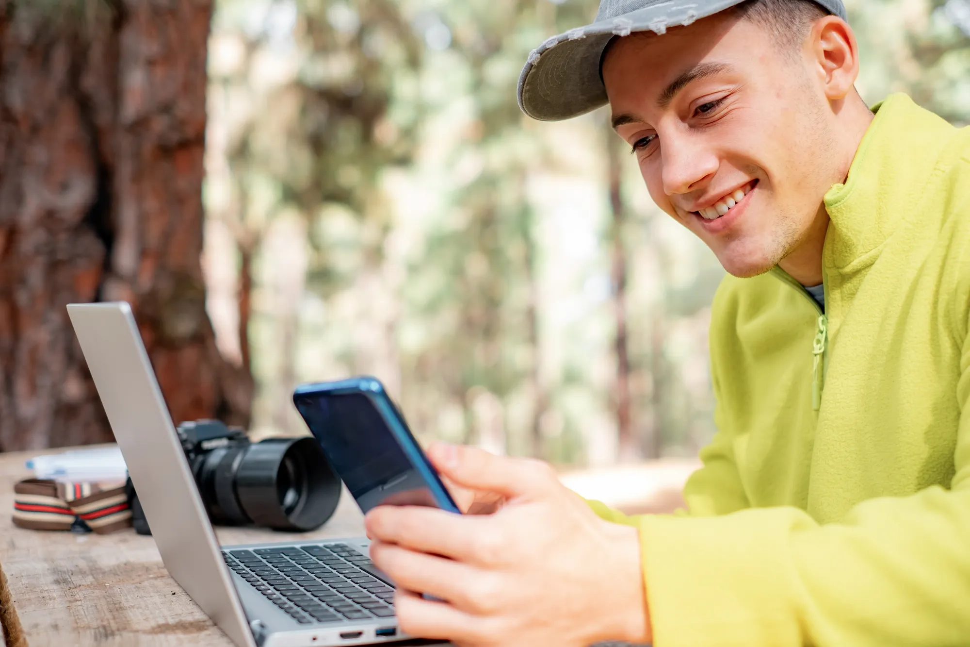 A man wearing a yellow shirt is holding a cell phone.