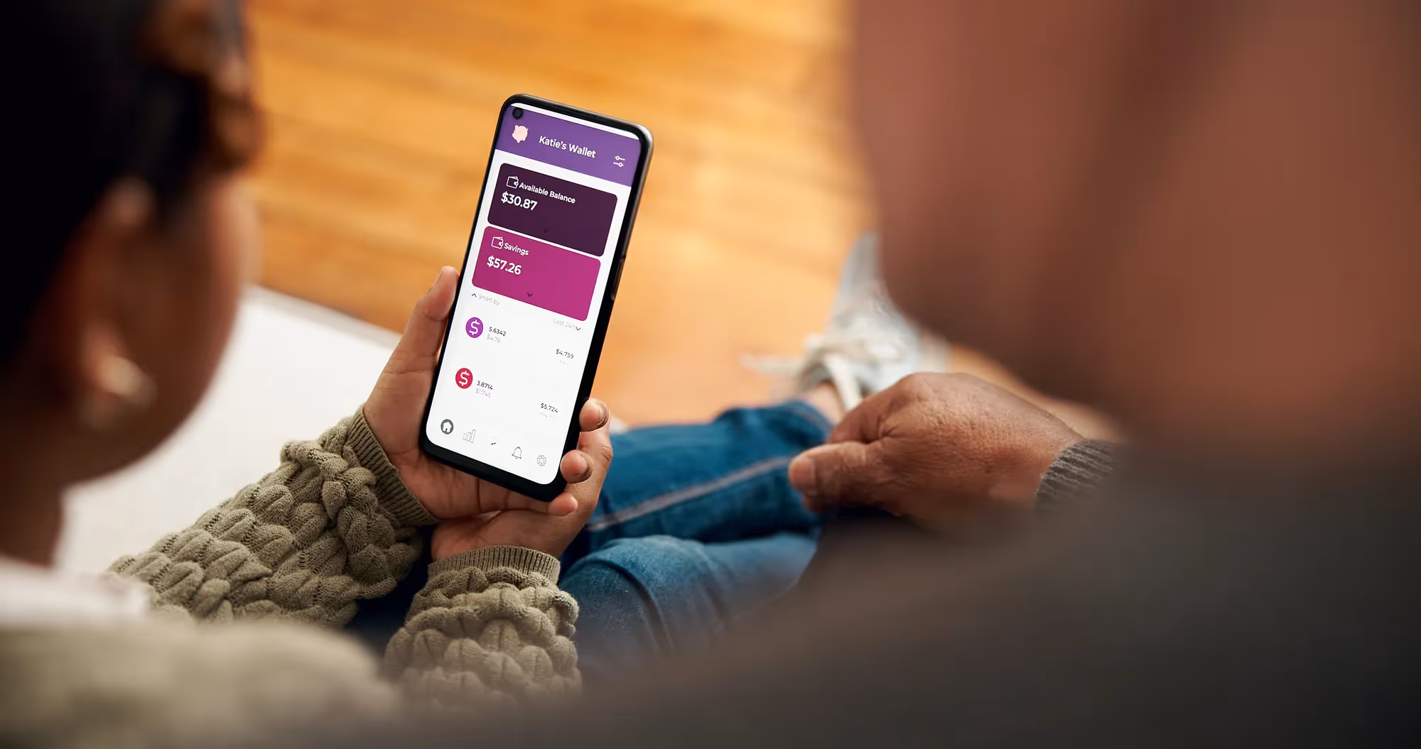 A person holding a cell phone with a purple screen.
