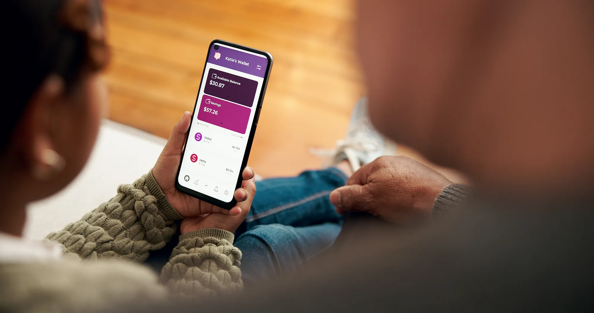 A person holding a cell phone with a purple screen.