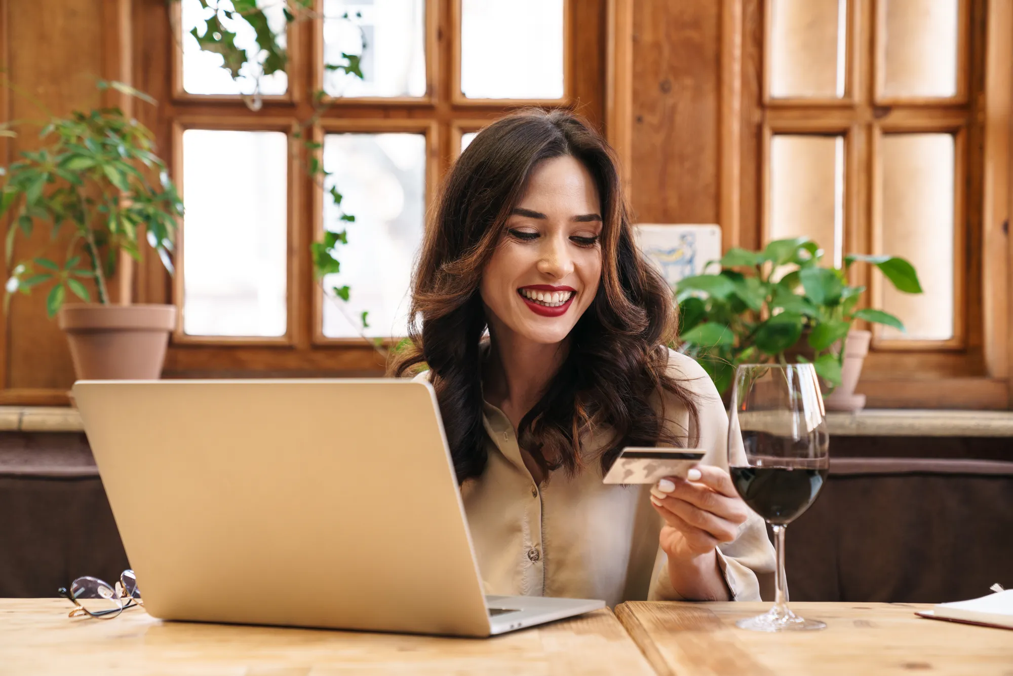 A woman sitting at a table with a laptop and a glass of wine.