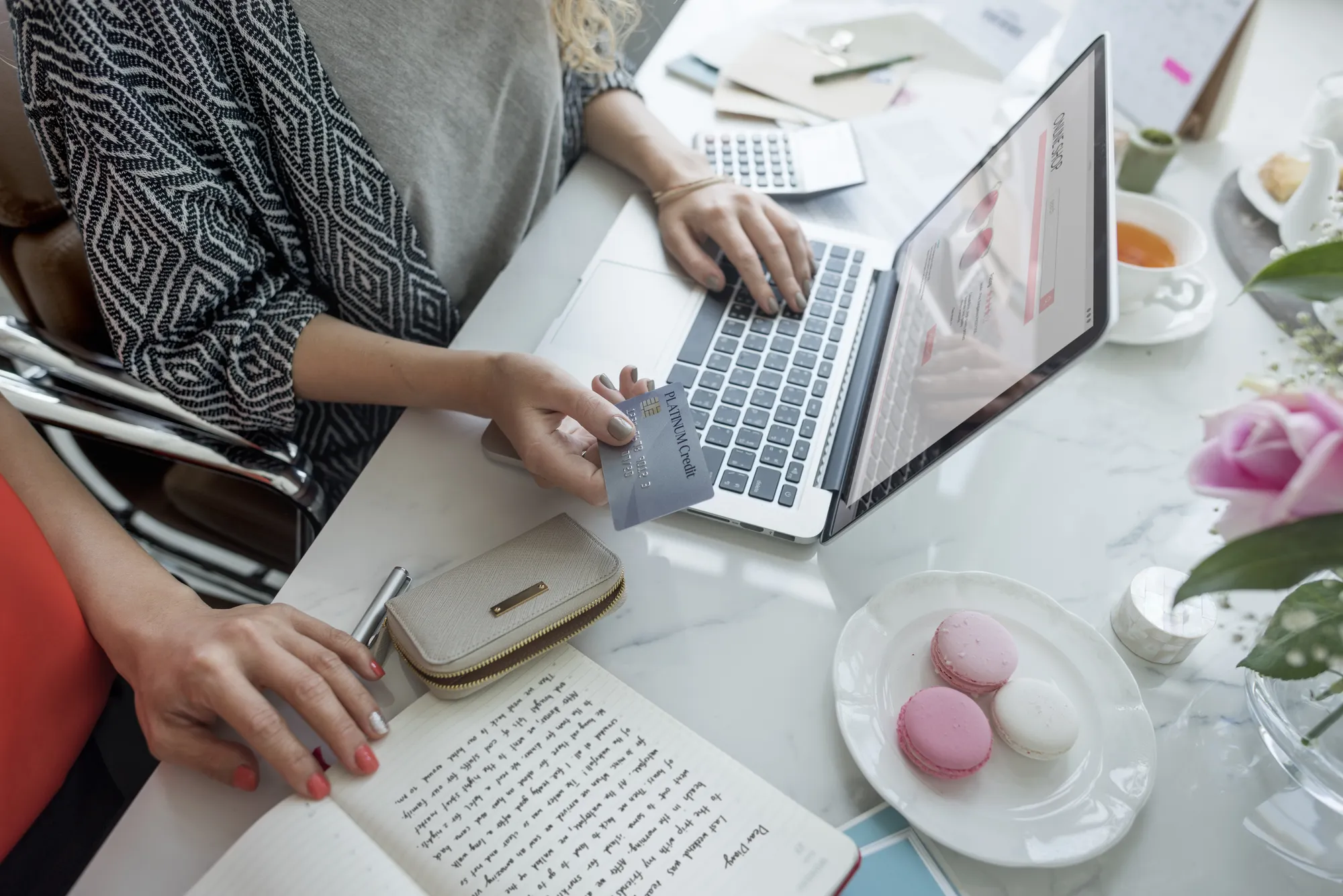 A woman holding a credit card and a laptop.