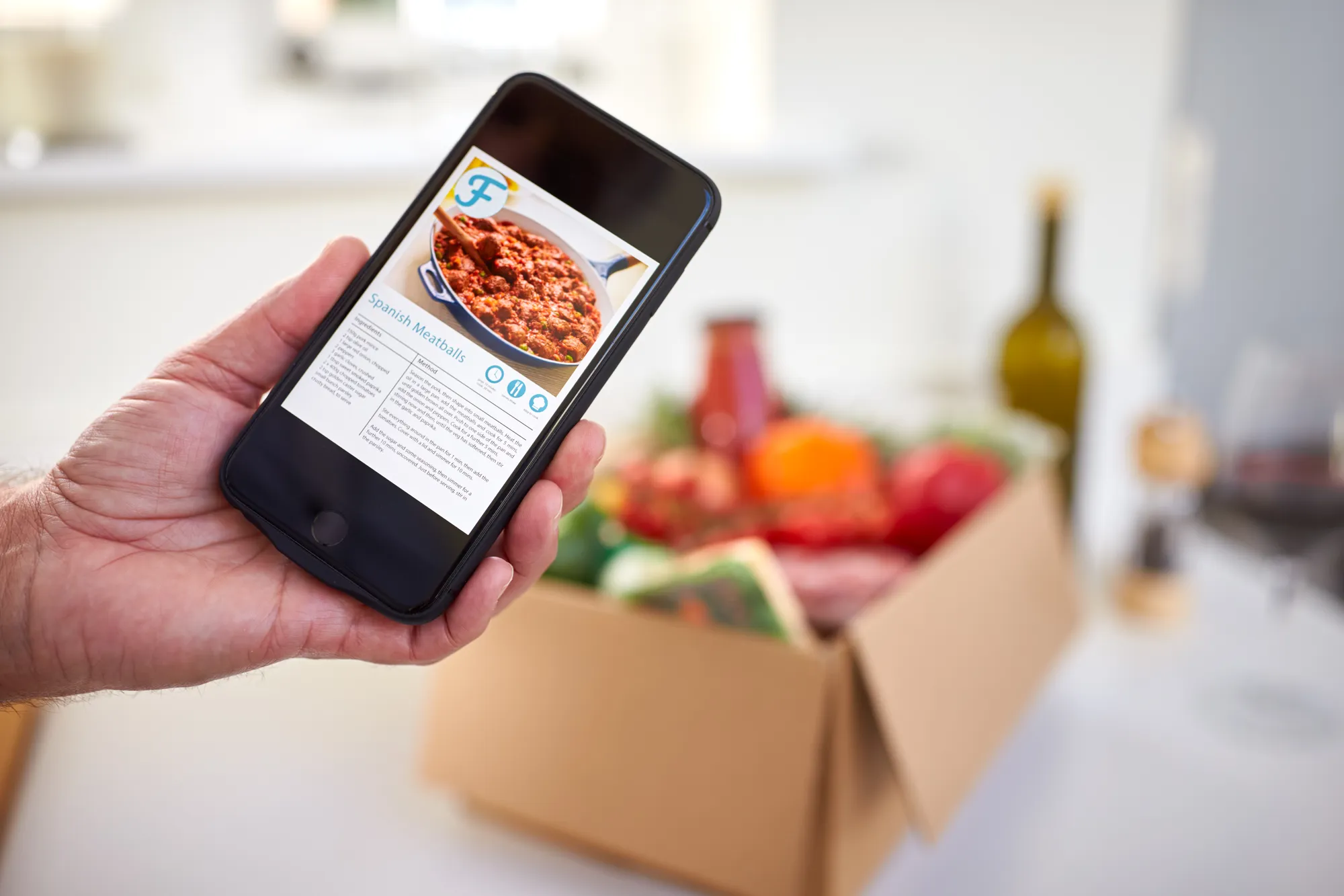 A person holding a cell phone with a recipe on the screen.