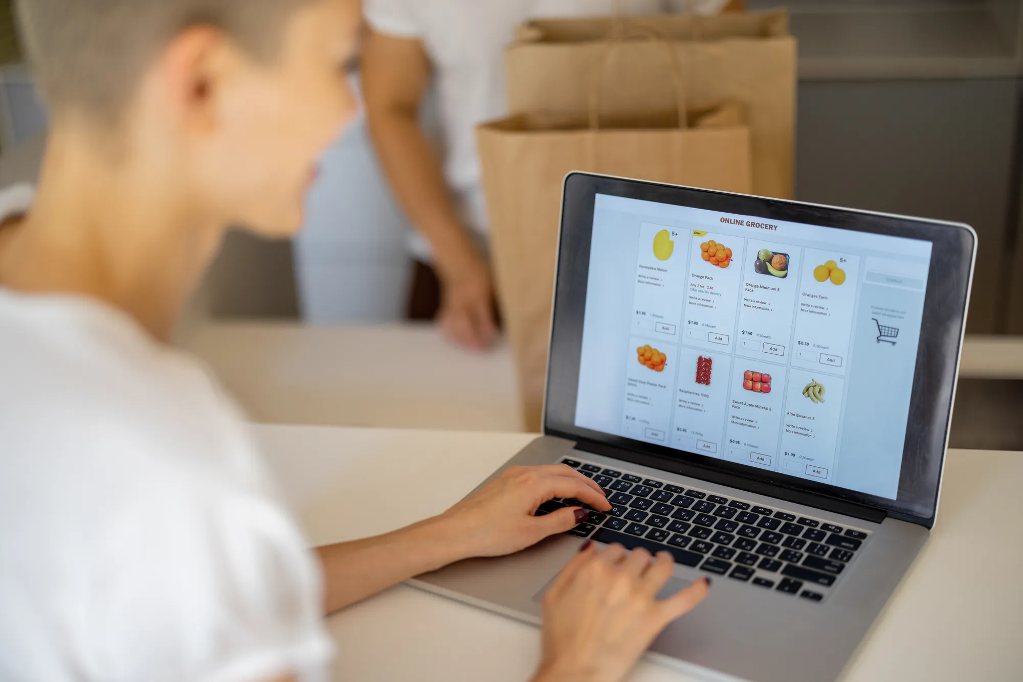 A woman is using a laptop with a screen displaying a list of fruits.