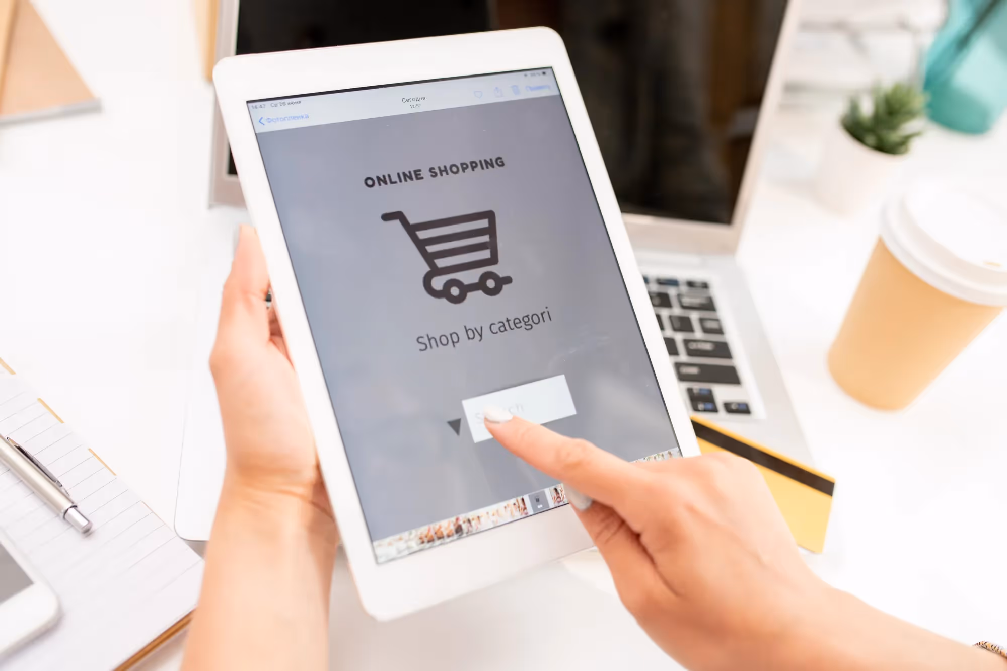 A person holding a tablet with the screen displaying the word online shopping.