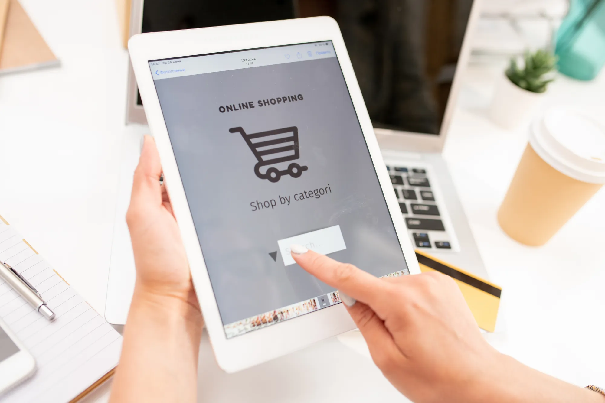 A person is holding a tablet with a shopping app on it.