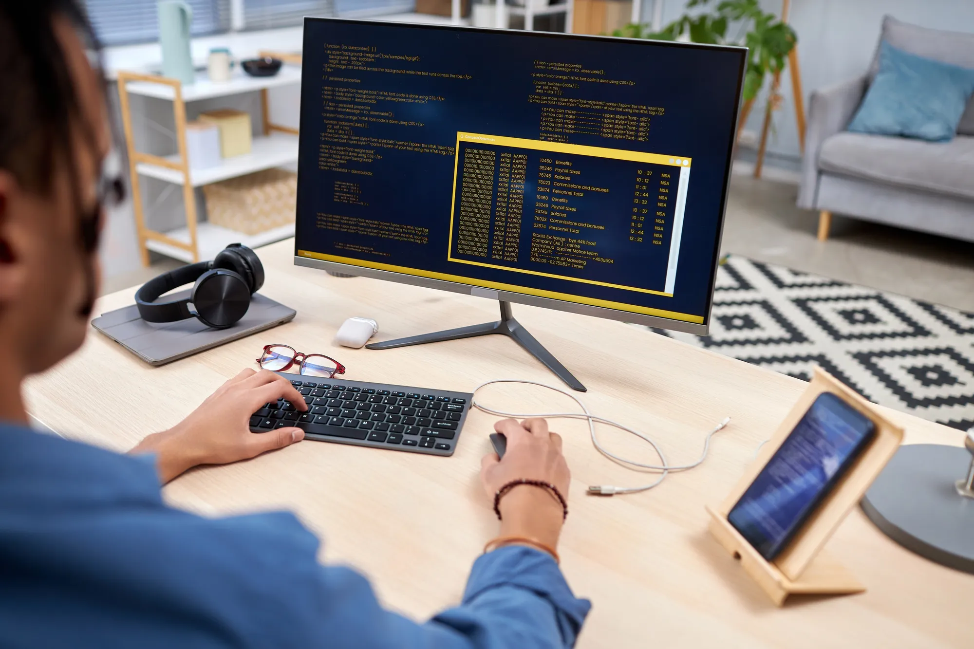 A man is typing on a computer with a monitor in front of him.