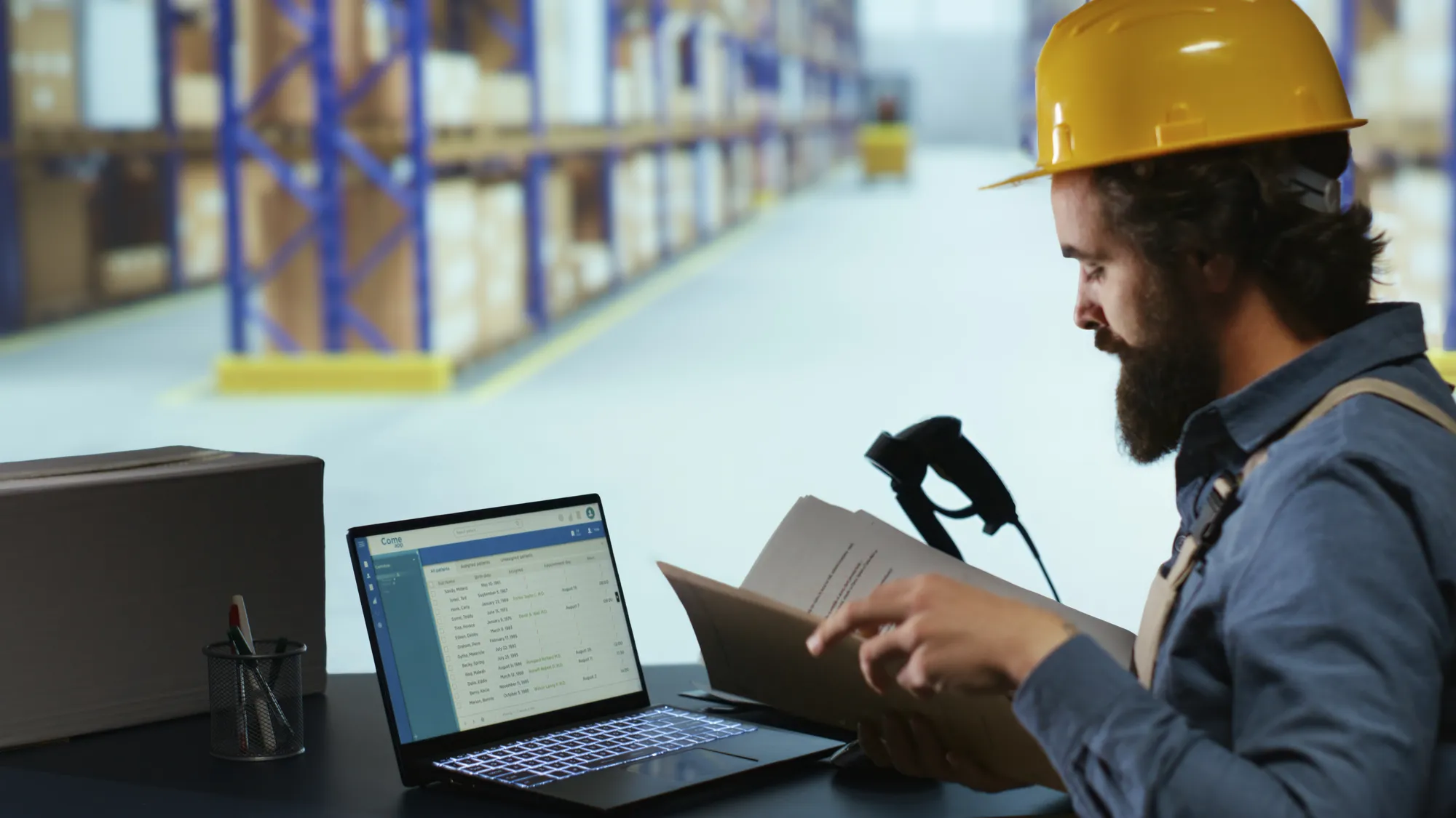 A man wearing a yellow helmet is looking at a laptop.