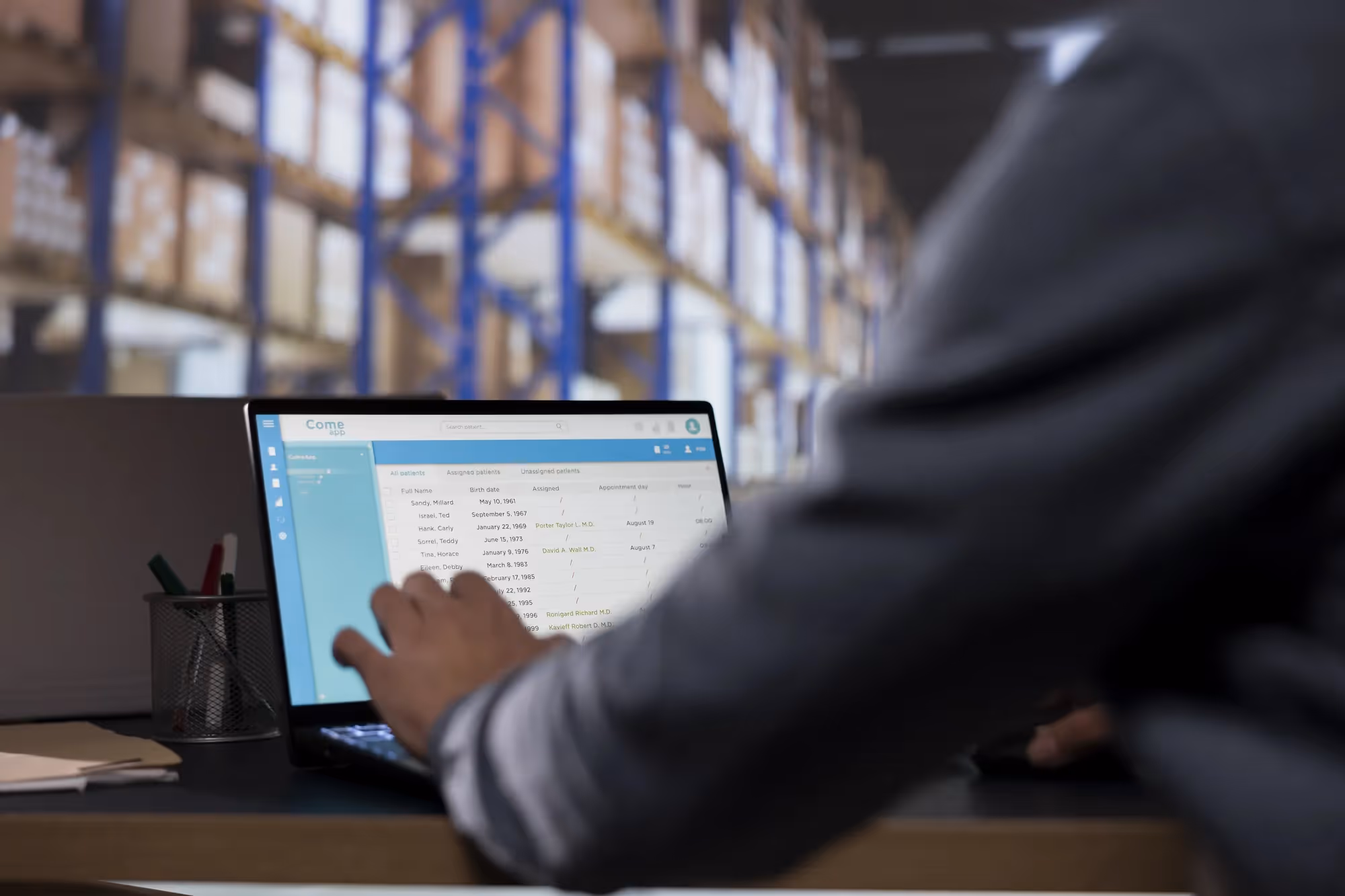 A man is using a laptop in a warehouse.