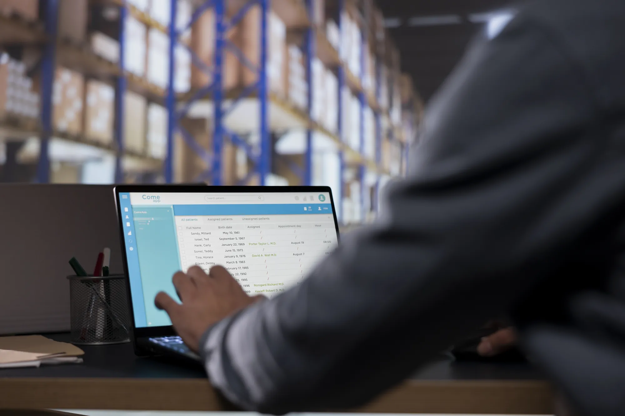 A man is using a laptop in a warehouse.