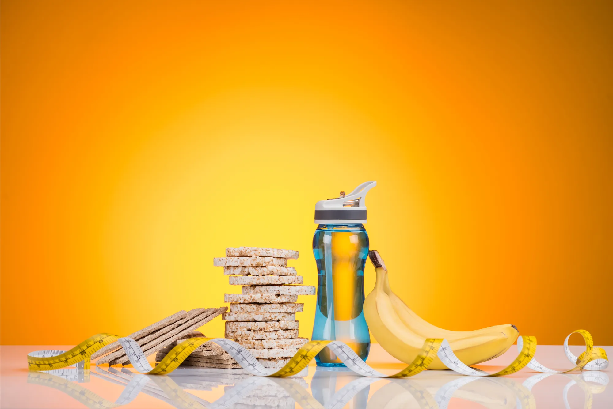 A stack of cereal, a banana, and a water bottle on a table.