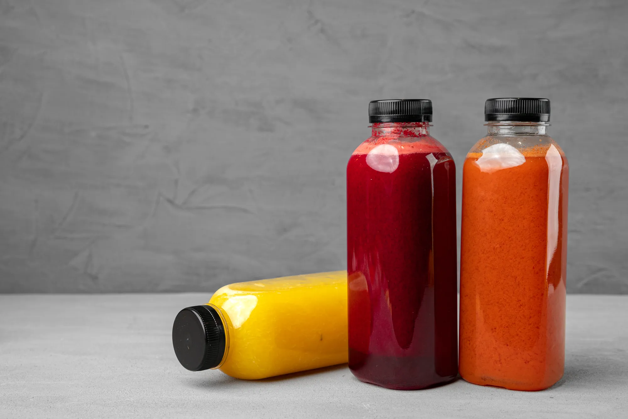 Two bottles of juice are on a table.