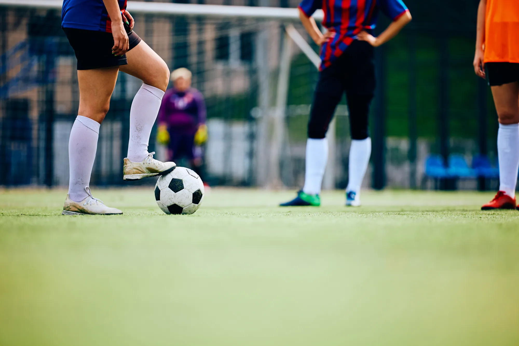 A soccer player is kicking a soccer ball on a field.