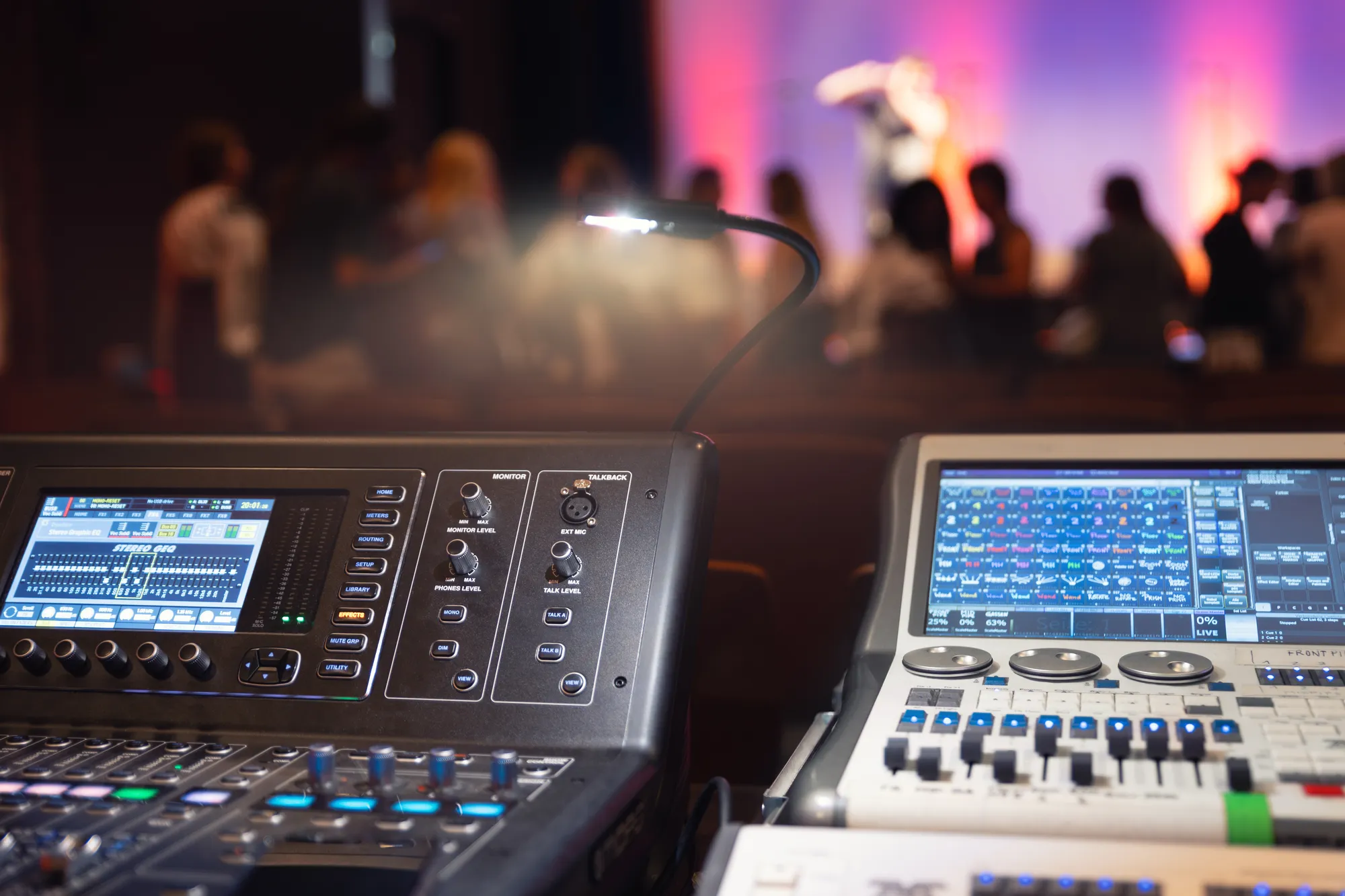 A black and silver audio mixing board with a light shining on it.