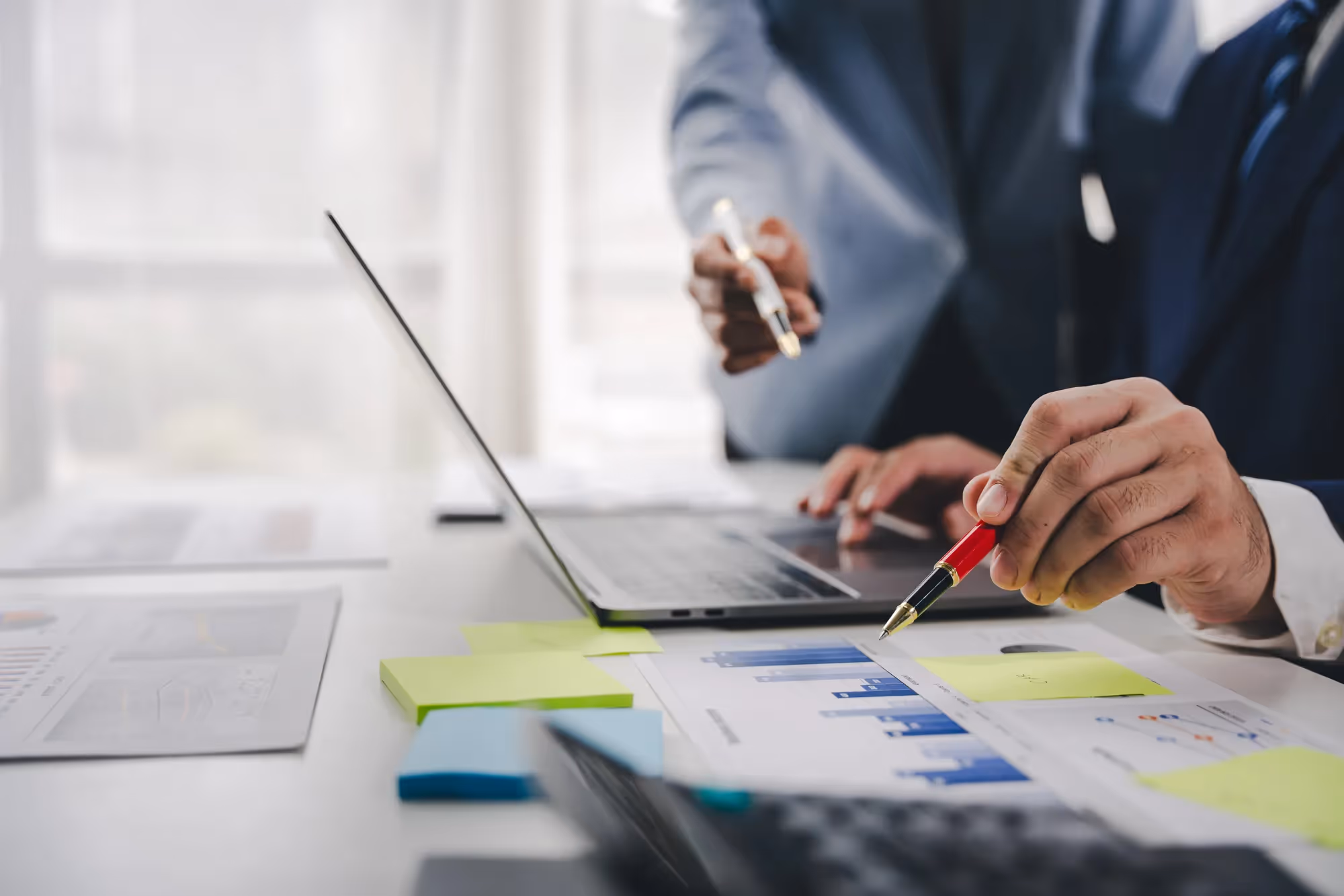 A man in a suit is writing on a piece of paper.