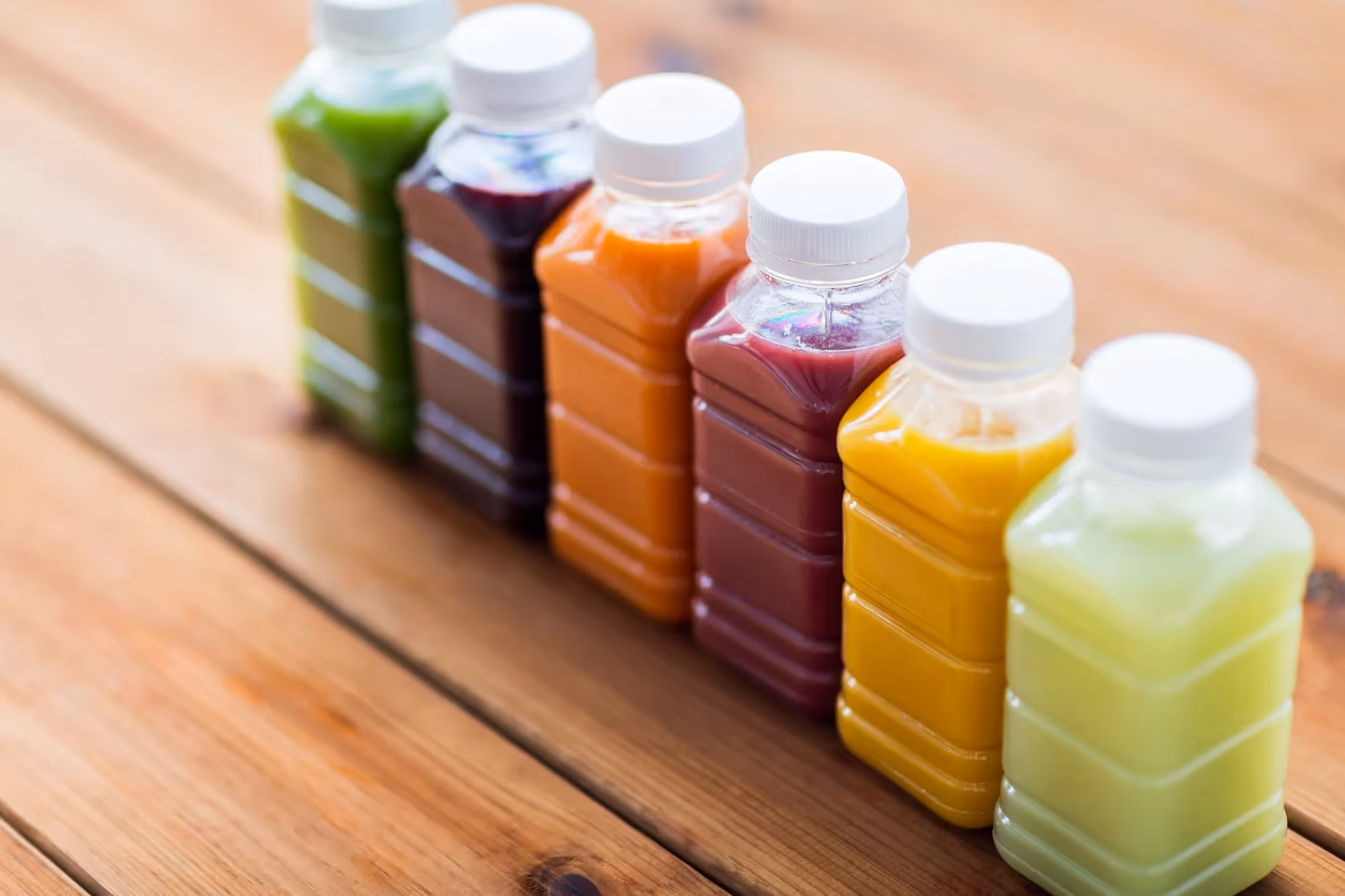 A wooden table with a row of bottles of juice.