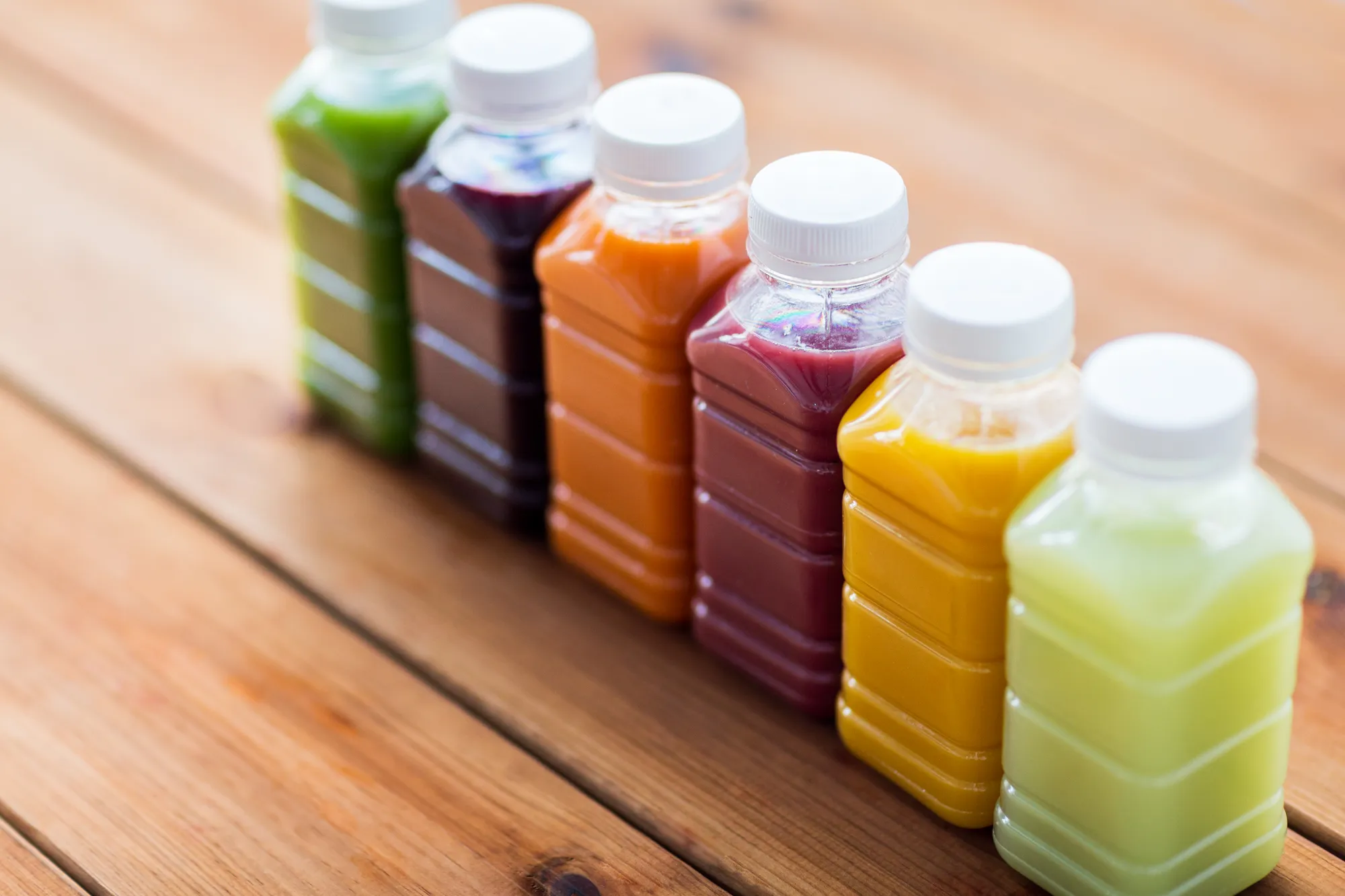 A wooden table with a row of bottles of juice.