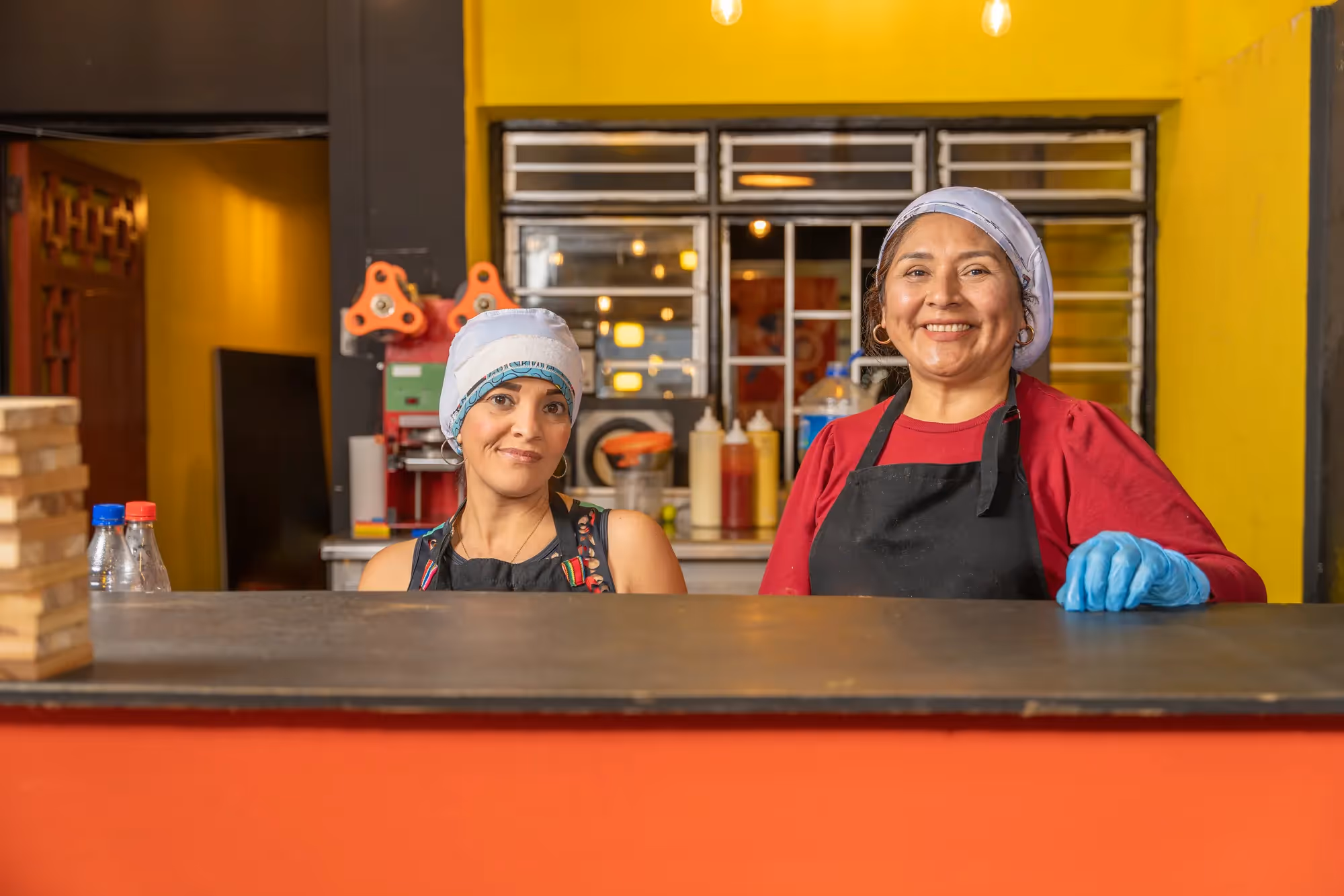Two women standing behind a counter in a restaurant.