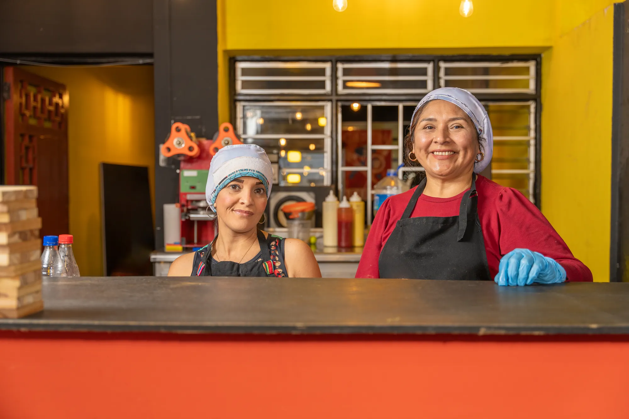 Two women standing behind a counter in a restaurant.